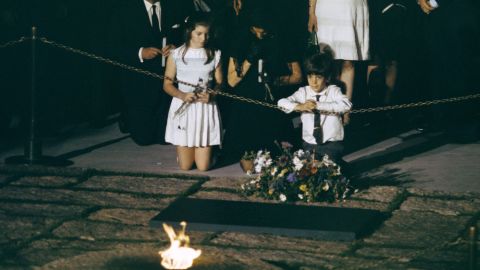 Caroline kneels beside her mother and brother at her father's grave in 1968.