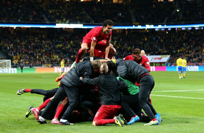 The Real Madrid star is mobbed after his hat-trick seals Portugal's place in the 2014 World Cup. 