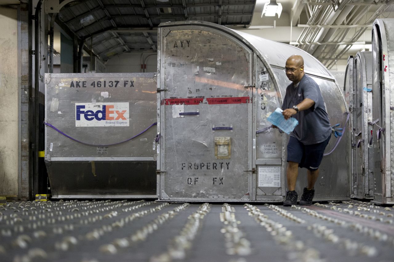 A FedEx worker moves containers full of packages at the cargo facility.
