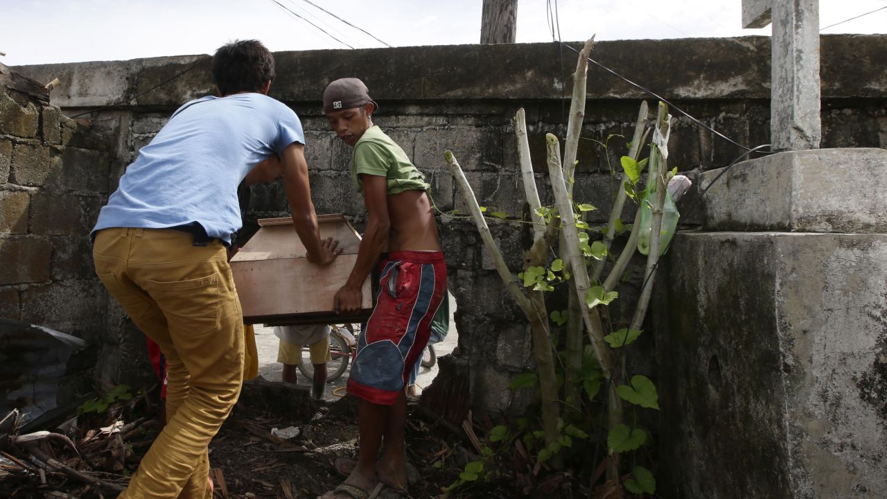 People carry a coffin through an opening in the wall of a public cemetery for burial in Tacloban on November 21.