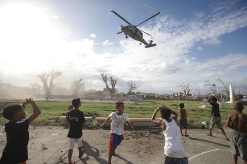 Typhoon survivors watch as a U.S. helicopter lands to deliver relief goods in Tanauan, Philippines, on Wednesday, November 20.  