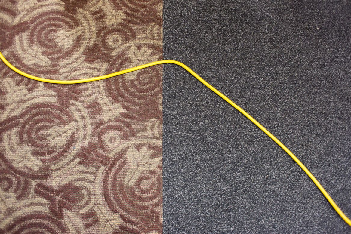 El cable de un aparato utilizado para limpiar el piso atraviesa la alfombra. 