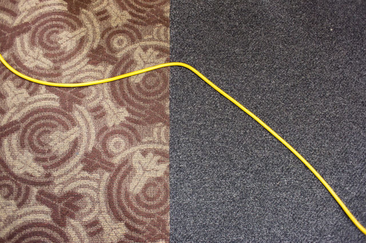 A floor cleaner's power cable crosses the carpet.