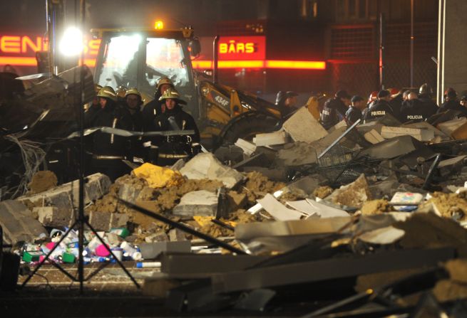 Rescue workers stand amid the debris from the collapse.