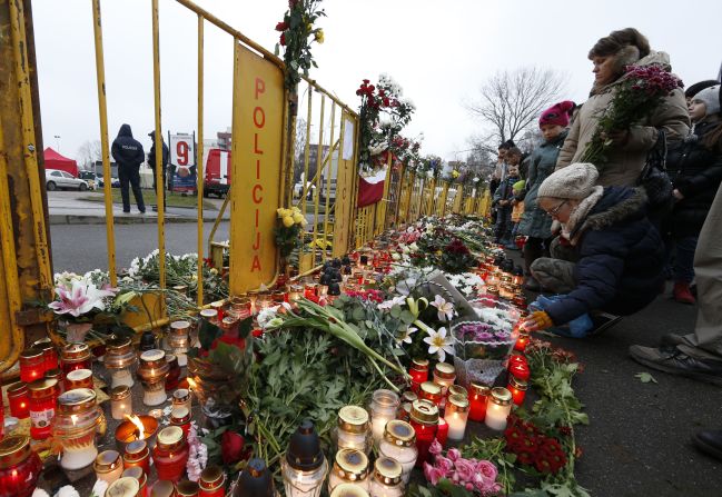 People place flowers and light candles in front of the Maxima supermarket in Riga, Latvia, on Saturday, November 23, two days after dozens of people reportedly died in a roof collapse. Riga Mayor Nils Usakovs said authorities suspect building materials stored on the roof caused it to collapse Thursday.
