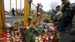 People place flowers and light candles in front of the Maxima supermarket in Riga, Latvia, Saturday, Nov. 23, 2013. Scores of people have died, including three firefighters, after an enormous section of roof collapsed at a Latvian supermarket in the country's capital, emergency medical officials said Friday. The roof fell Thursday evening in the Latvian capital of Riga as customers were doing after-work shopping.  Preliminary reports indicate the roof caved in due to either faulty construction or building activities on the roof, where workers were creating a garden area and children's playground for a new high-rise residential building adjacent to the supermarket. (AP Photo/Mindaugas Kulbis)
