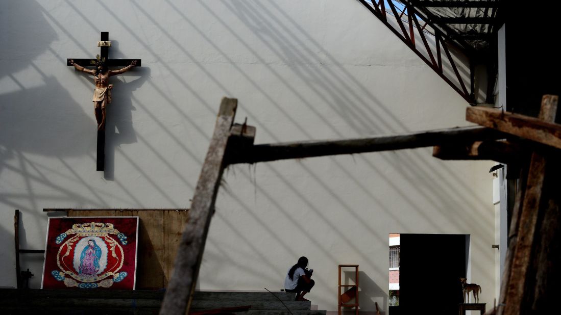 A woman rests inside the damaged Our Lady of Guadalupe shrine in Tacloban, Philippines, on Sunday, November 24.