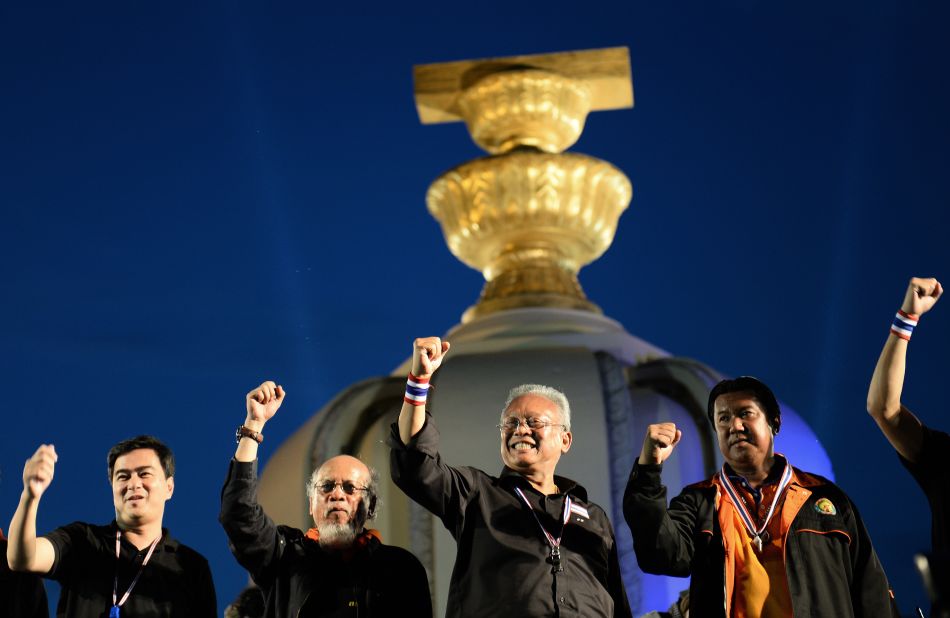 Thai opposition leaders Suthep Thaugsuban, center, and former Prime Minister Abhisit Vejjajiva, left, clinch their fists as they appear on stage during a rally at Democracy Monument in Bangkok Sunday.