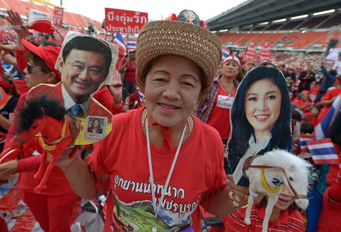 Thai pro-government 'red shirts' hold pictures of Thaksin and Yingluck Shinawatra as she gather at Rajamangala Stadium in Bankok Sunday.