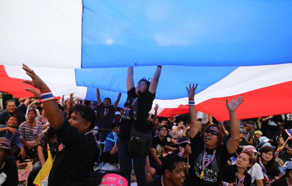 Anti-government protesters ripple a giant Thai flag.
