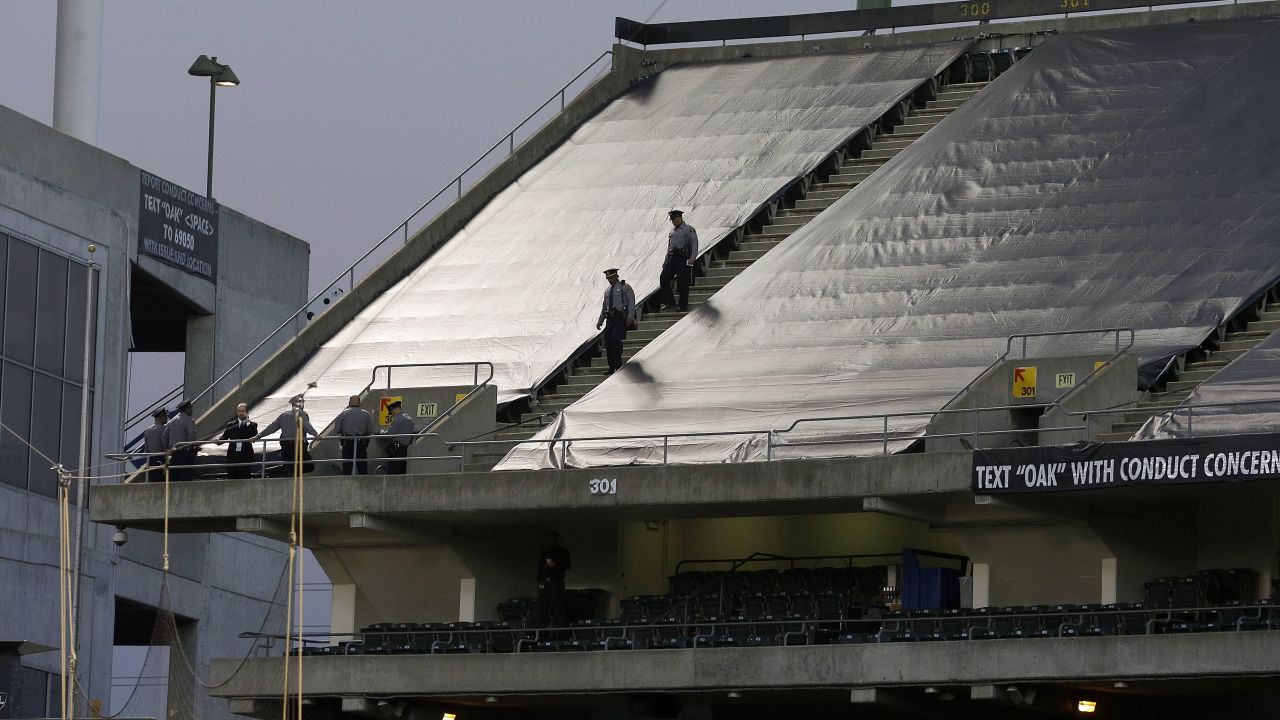 Authorities walk the upper deck of O.co Coliseum after, authorities say, a football fan jumped from the third deck.