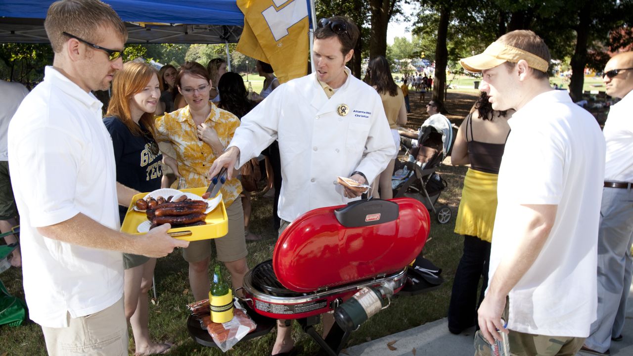 Jessica Keesee, center left, and her husband, Christian Pierce, center, serve up lunch from the grill as they tailgate at Georgia Tech.