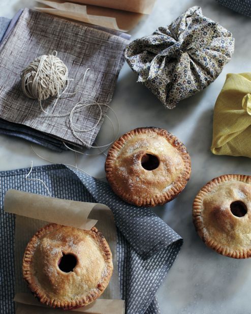Give guests a parting gift: a single-serving pie wrapped in a square of cotton. If they're too full from turkey and fixings, they'll still get to enjoy a home-baked dessert<br /><strong>Supplies:</strong> 5-inch pies, in aluminum tins, Medium-weight cotton or linen fabric, Sewing machine and supplies, Twine and waxed paper<br /><strong>How-to: </strong>1. Make pies  2. Cut 17 1/2-inch squares from fabric. Press edges under 1/4 inch, then another 1/4 inch. Hem all the way around. (We made these, but store-bought  napkins work just as well. 3. Tie a piece of waxed paper around each pie, then center atop a fabric square. Drape opposite corners of square over pie, then tie remaining corners in a square knot.