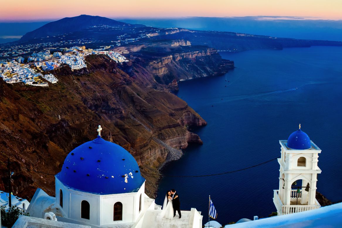 "As a photographer, when a couple is flying you across the world to such a picturesque location as Santorini, Greece, it's imperative to go home with at least one epic photo that shows the stunning backdrop of this ancient white and blue city," says Chrisman. Mauricio Arias of Chrisman Studios posed his subjects and told them to keep interacting while he climbed high enough to capture the beautiful scene. 