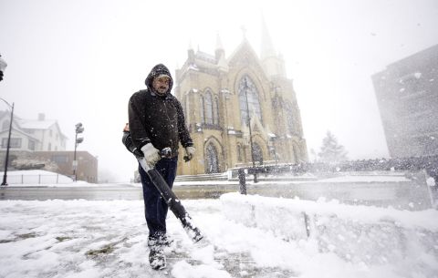 Mark Swigart uses a leaf blower to remove snow from the sidewalks November 26 in Pittsburgh.