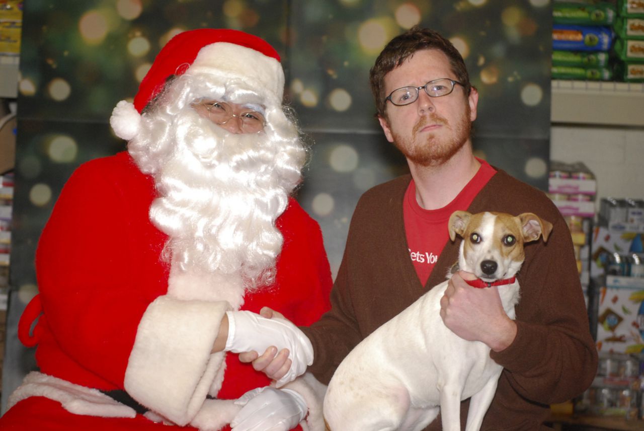 Terry Nagurney le da la mano a Santa con su perra, Abby, en su regazo. Esta foto fue tomada durante un evento de beneficencia en PetSmart, en Atlanta, para Furkids, el refugio para gatos más grande de Georgia, donde no hay muertes y los animales no se mantienen en jaulas.