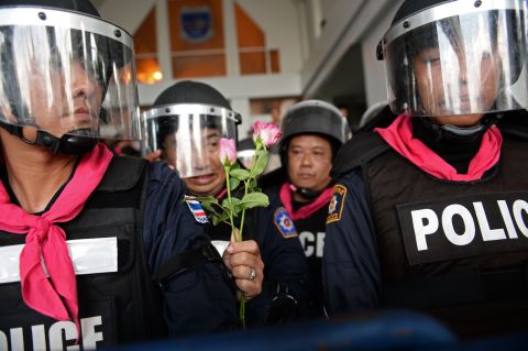 A Thai riot policeman holds flowers which were offered to him by opposition protesters during a rally at a government complex in Bangkok on November 27, 2013.