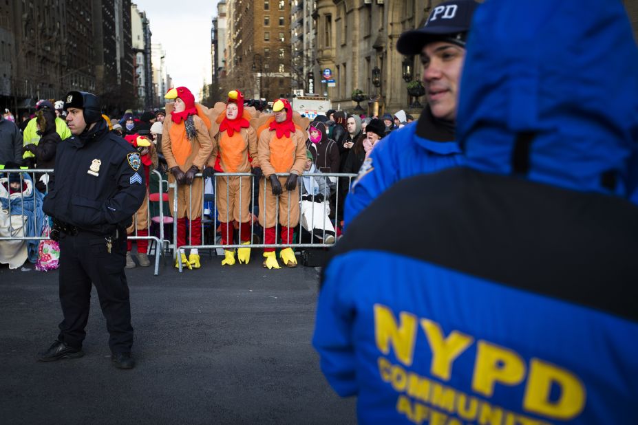 Spectators stand behind police barricades as they wait for the parade to start.