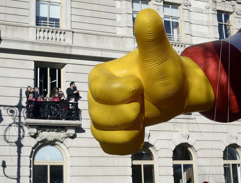 The Ronald McDonald balloon appears to give a thumbs-up to observers on a balcony.