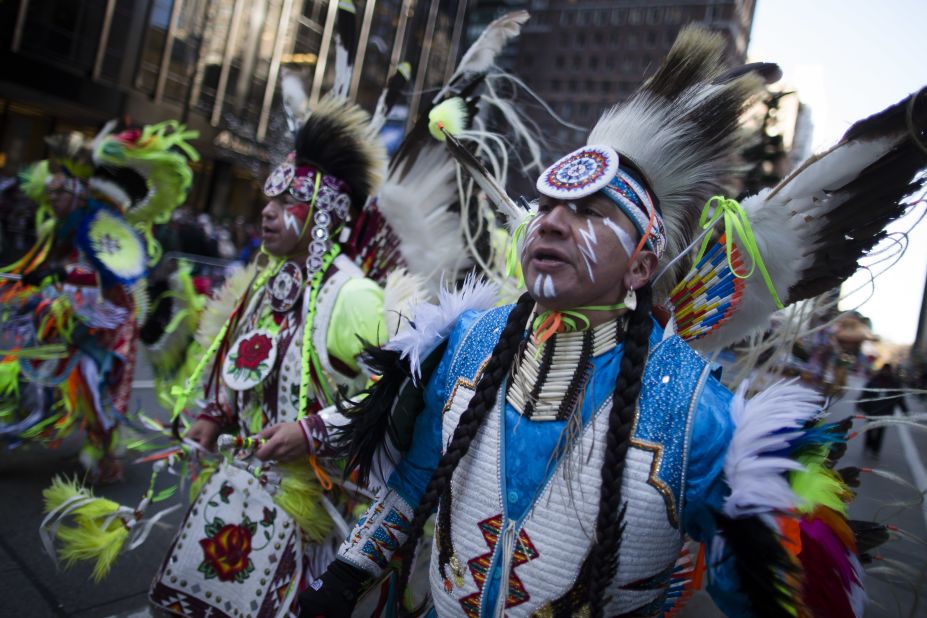 A Native American performance group marches down Sixth Avenue.