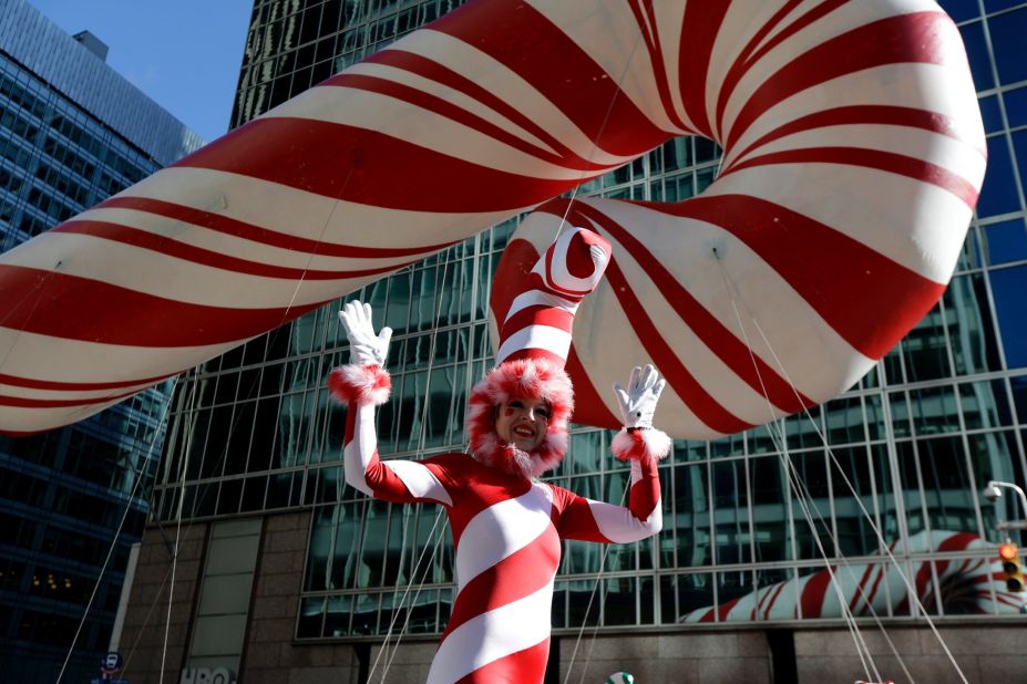 A performer on stilts walks near a candy cane balloon.