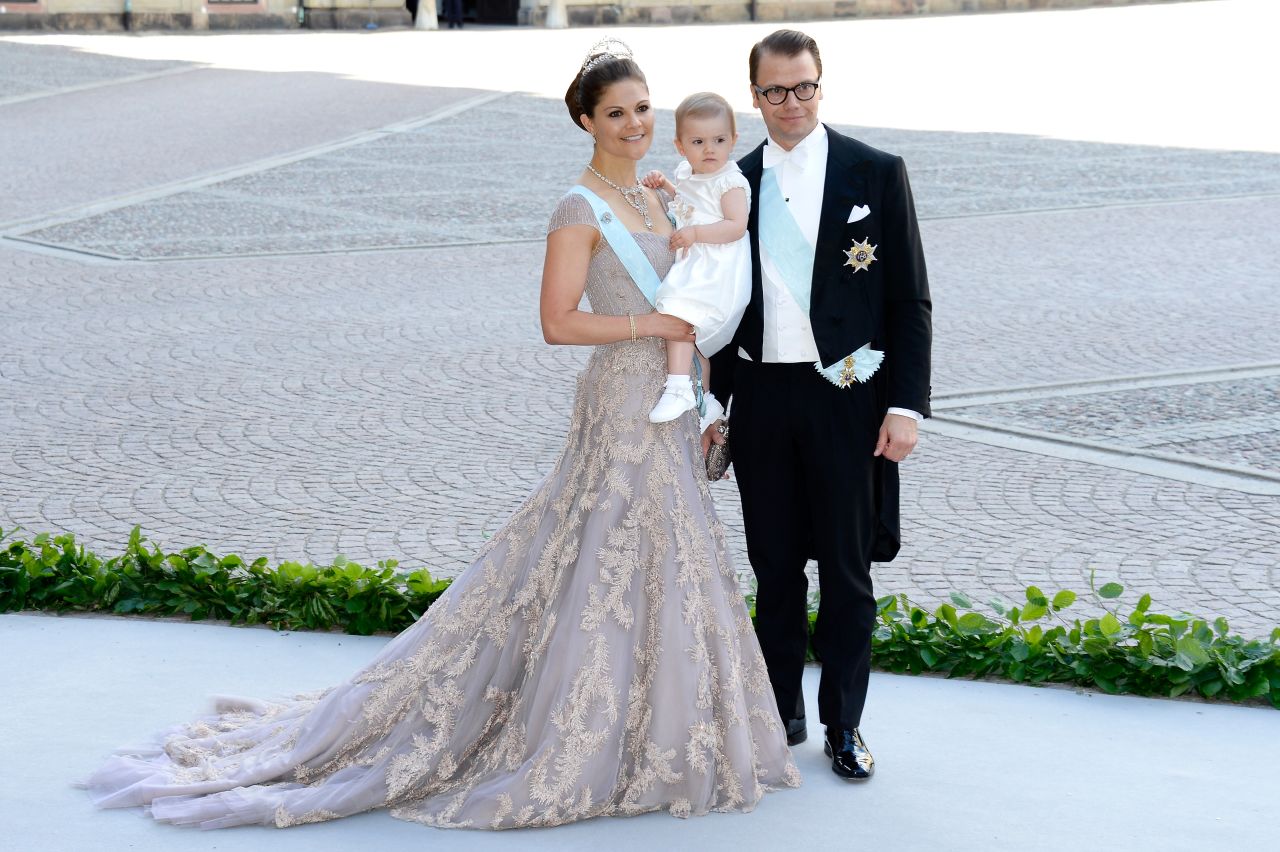 Crown Princess Victoria of Sweden flies the flag for Scandinavian style, often wearing romantic dresses in shimmering pastel hues. Here she is with her daughter Princess Estelle of Sweden, and husband Prince Daniel at the wedding of her sister Princess Madeleine in Stockholm. 