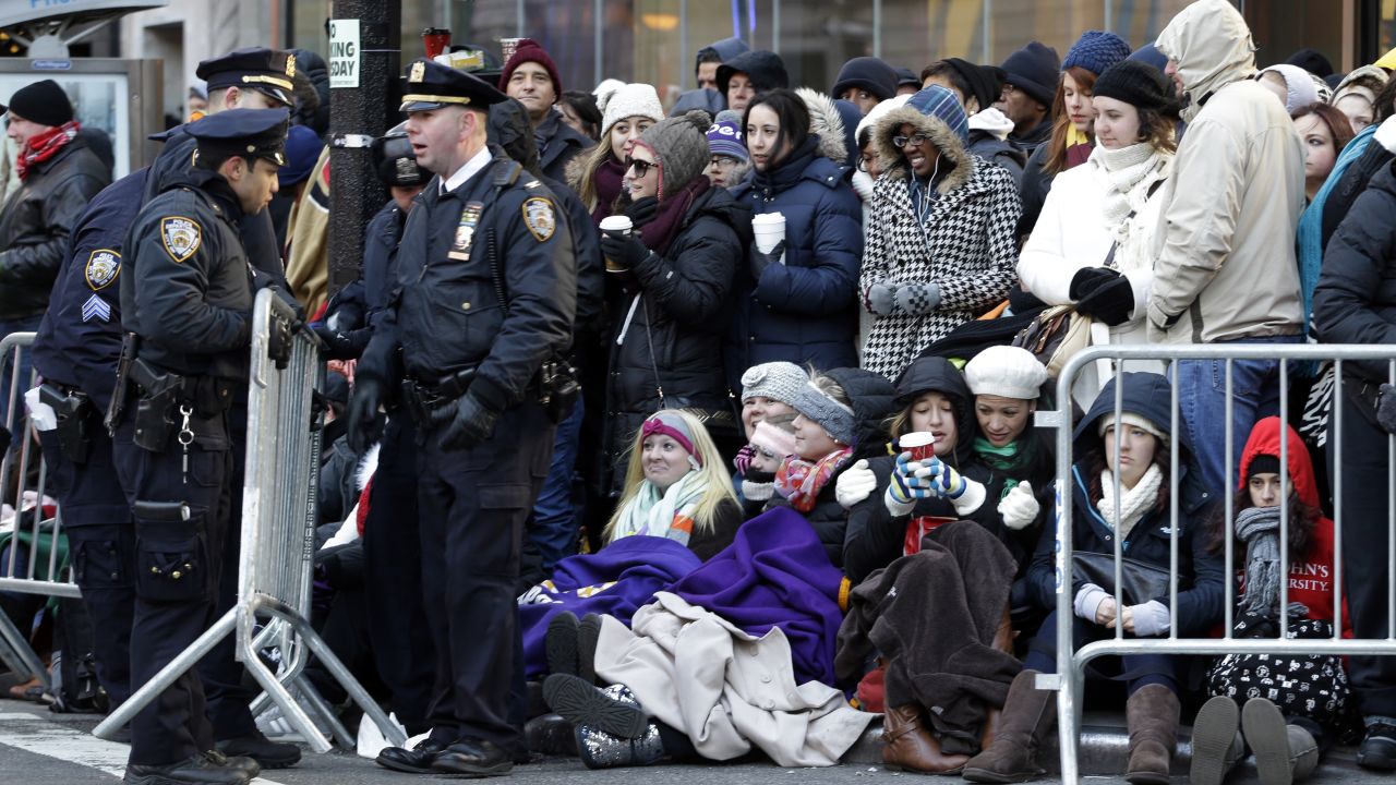 Police officers adjust a barricade as people wait in cold weather along the route of the Macy's Thanksgiving Day Parade on Thursday, November 28, in New York. 