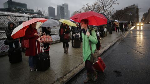 Passengers wait for a BoltBus to arrive during a light rain on Wednesday, November 27,  in New York. A wall of storms packing ice, sleet and rain threatened to suspend holiday travel plans as millions of Americans took to the roads, skies and rails. 