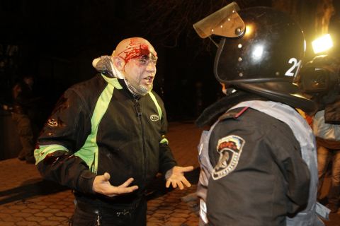 A bleeding protester shouts at a police medic after police pushed protesters off the street leading to the presidential administration building on December 1.