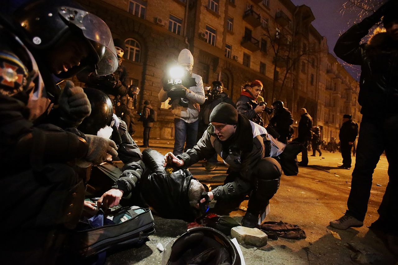Police and protesters look at an injured person near the presidential office on December 1. 