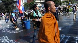 A Thai Buddhist monk watches as opposition protesters clash with police outside Government House in Bangkok on December 1, 2013.