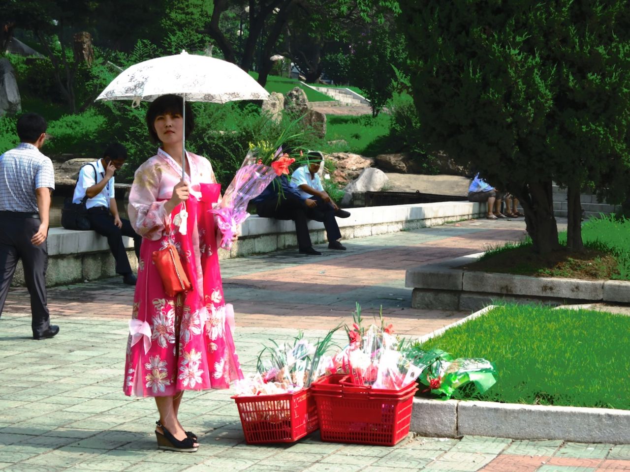 A flower vendor beside a Kim Il Sung statue in Pyongyang sells bouquets of flowers to locals and tourists to lay at the foot of the statue.