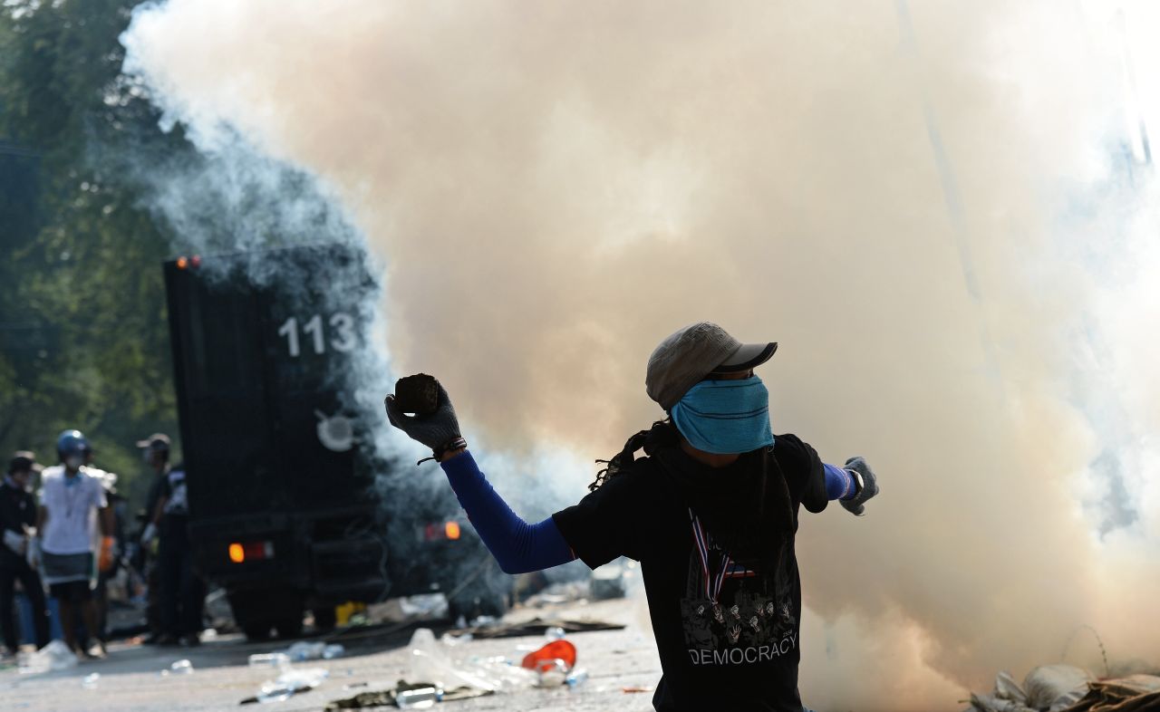 A protester throws a stone at police Monday, December 2, during a rally outside government headquarters in Bangkok, Thailand.