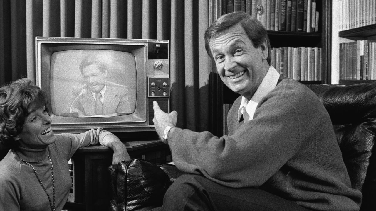 American game show host Bob Barker points to himself on a nearby television screen as his wife Dorothy Jo Barker (1924 - 1981) looks on and laughs, November 4, 1977.