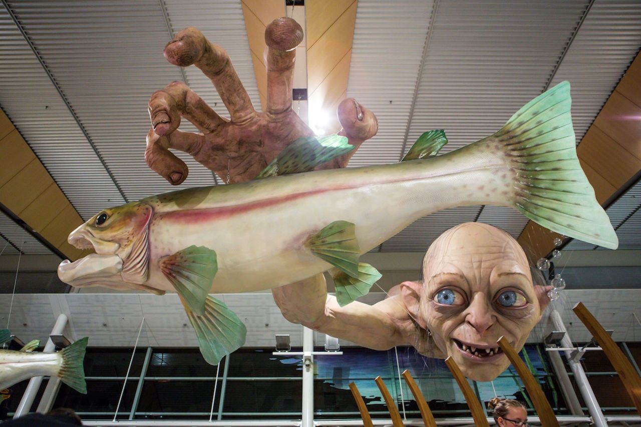 Te deseo suerte si quieres comer con esa criatura observándote desde arriba. Las nuevas esculturas del Aeropuerto Internacional Wellington, inspiradas en "El Hobbit" se unen a esta instalación actual que muestra a Gollum intentando alcanzar truchas, la cual ha estado suspendida sobre el área de restaurantes del aeropuerto desde finales del año pasado.