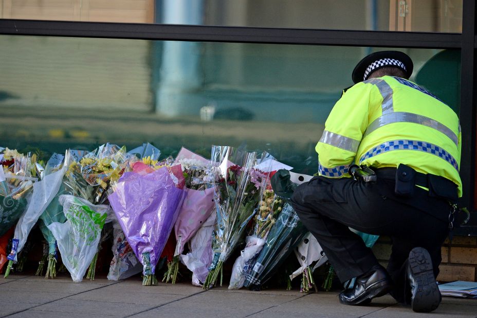 A police officer lays flowers new the pub on Sunday, December 1.
