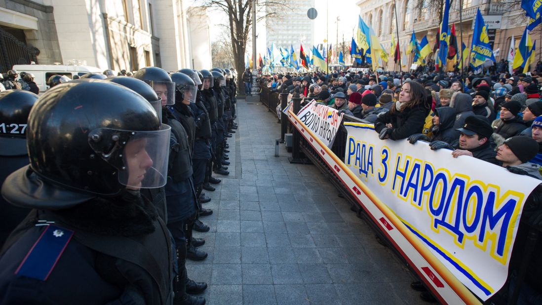 Police stand guard opposite a sea of protesters near the Ukrainian parliament in Kiev on December 3.