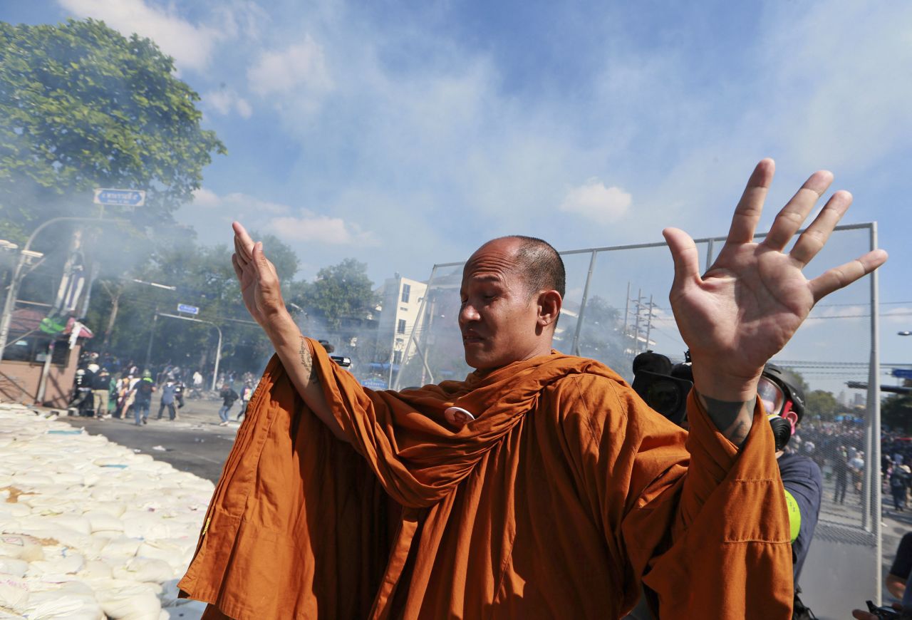 DECEMBER 3 - BANGKOK, THAILAND: A Buddhist monk raises his hands to policemen in Bangkok. <a href="http://edition.cnn.com/2013/12/03/world/asia/thailand-protests/index.html?hpt=hp_t2">Tensions in the capital eased after police took down barricades </a>and allowed anti-government demonstrators to enter the government buildings. Policemen shook hands with demonstrators, ushering them past. Protesters responded with cheers and applause, claiming victory.