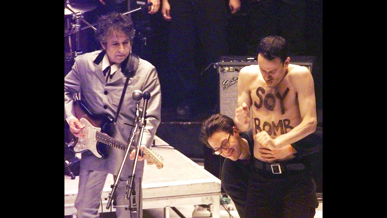 Performance artist Michael Portnoy is taken off stage during Dylan's performance at the Grammy Awards in 1998. Portnoy had been hired as part of the background dancers for the performance, but his shirtless interruption was not planned and he was carted off stage.