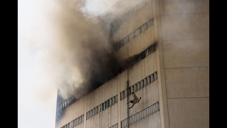 <strong>May 9:</strong> A man overcome by fumes falls out of a window as a fire burns at the Lahore Development Authority Plaza in Lahore, Pakistan.