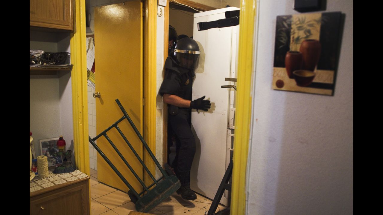 <strong>September 25:</strong> Police push away a refrigerator as they enter the Madrid apartment of Maria Isabel Rodriguez Romero. Romero and her family of six were evicted by the State City Hall Housing Company. Spain is slowly emerging from a two-year recession, but it still has a high unemployment rate and evictions have rapidly increased as borrowers are unable to pay their mortgages.