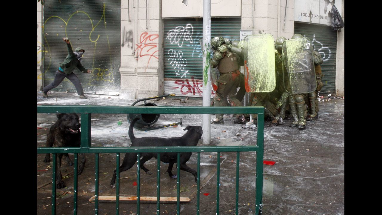 <strong>April 11:</strong> A protester aims a rock at a huddle of shielded riot police after students held a march demanding free education in Santiago, Chile.
