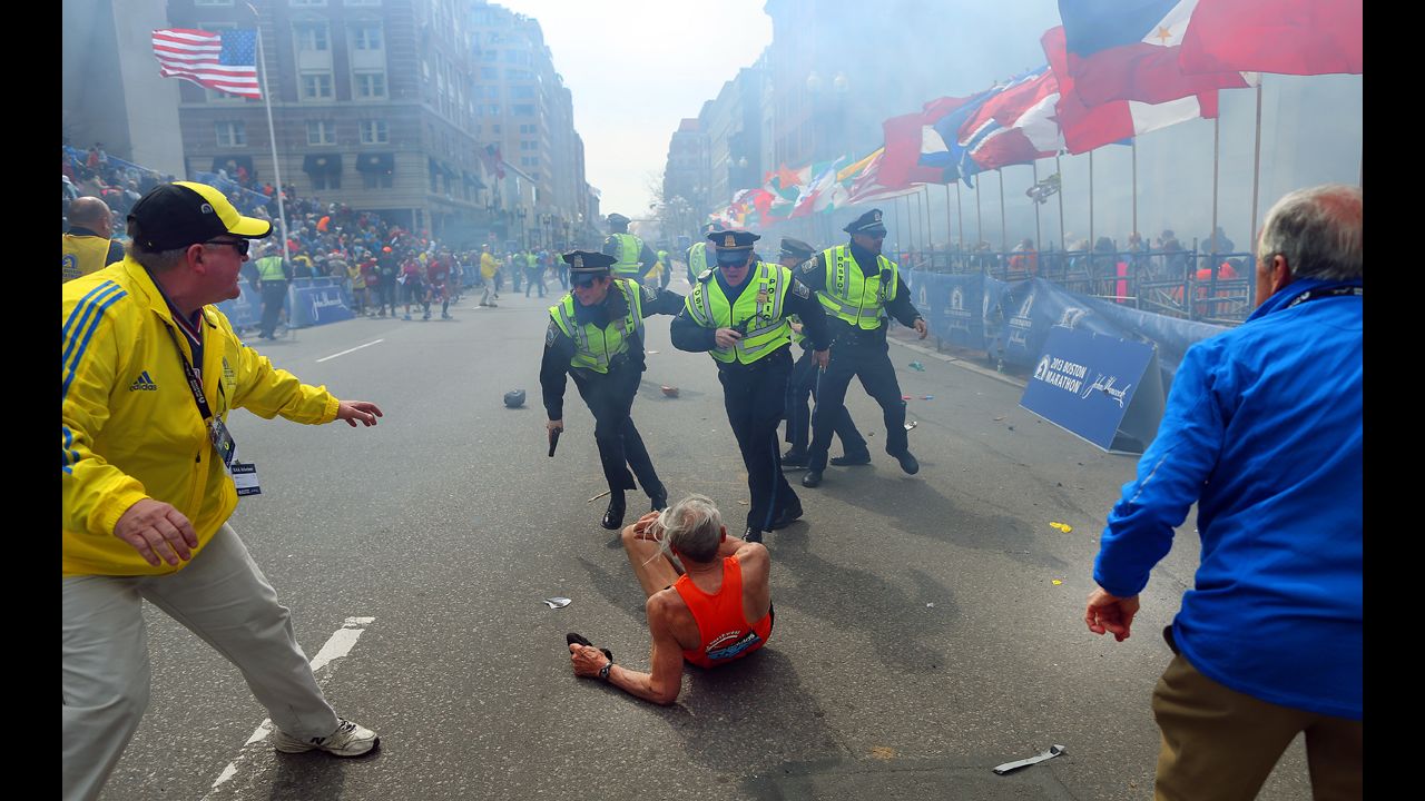 <strong>April 15:</strong> Police officers stand over marathon runner Bill Iffrig as a second explosion sounds near the finish line of the Boston Marathon. Three people were killed and at least 264 were injured in the terror attack.
