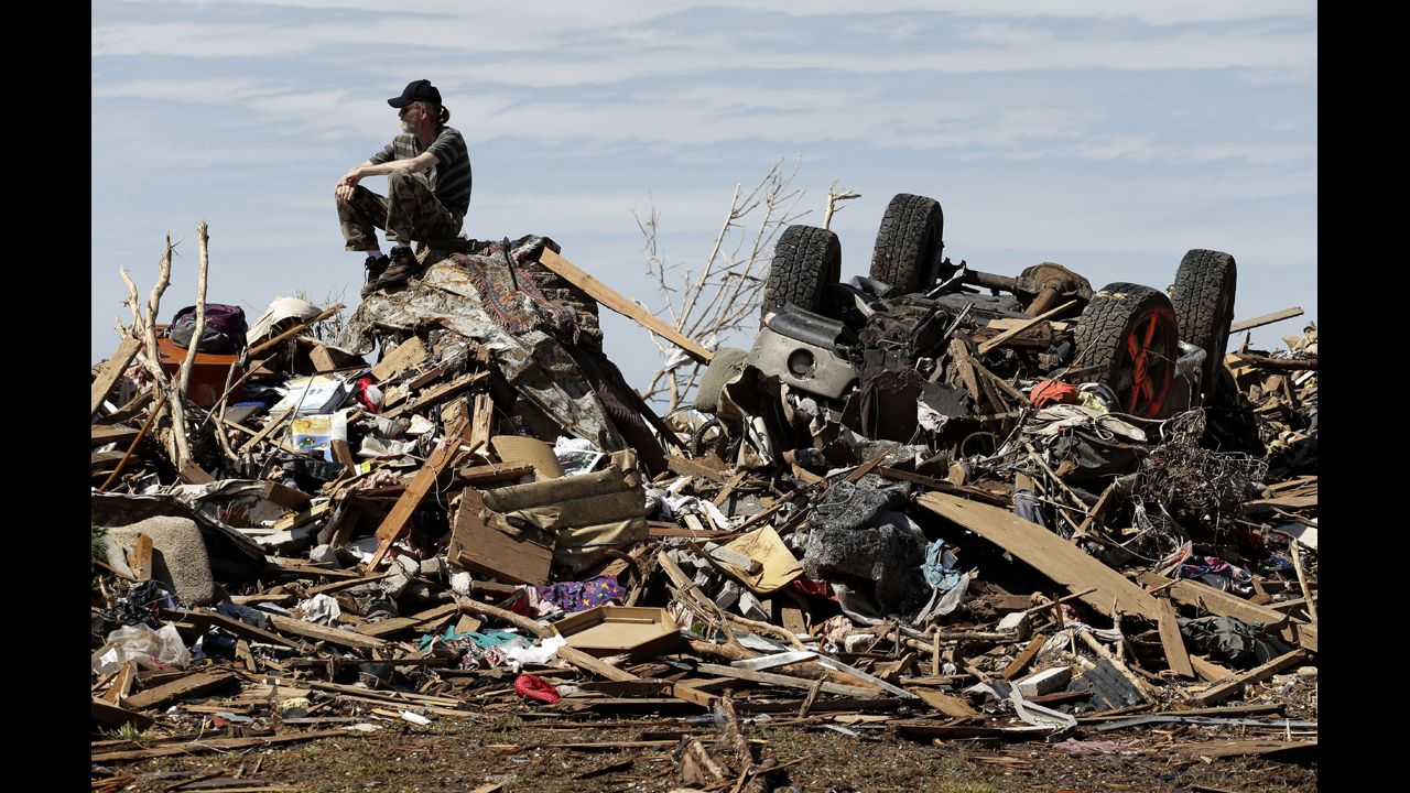 <strong>May 23:</strong> David Lee Estep waits for his parents on a pile of rubble that used to be their home in Moore, Oklahoma. Moore was hit by a massive EF5 tornado that killed 24 people, including seven students at an elementary school.