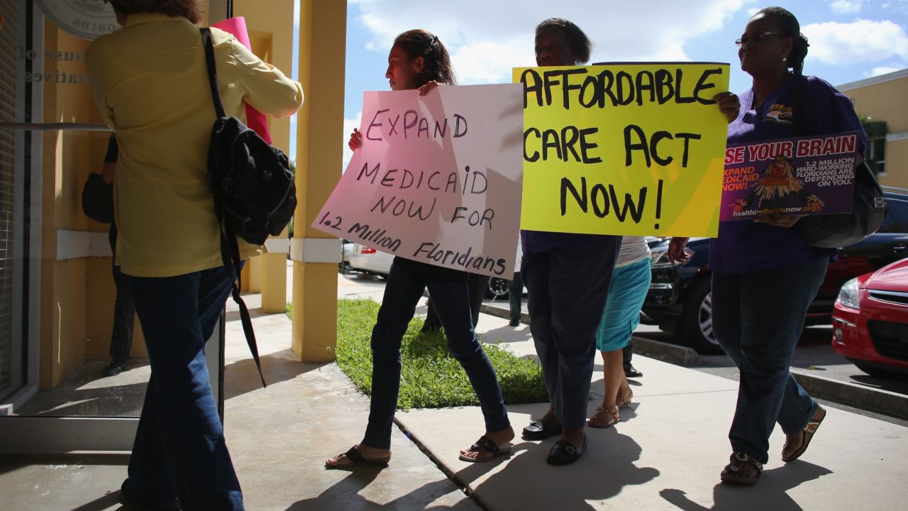 Demonstrators walk into a Florida state legislator's office to protest the state's stance against the expansion of Medicaid. 