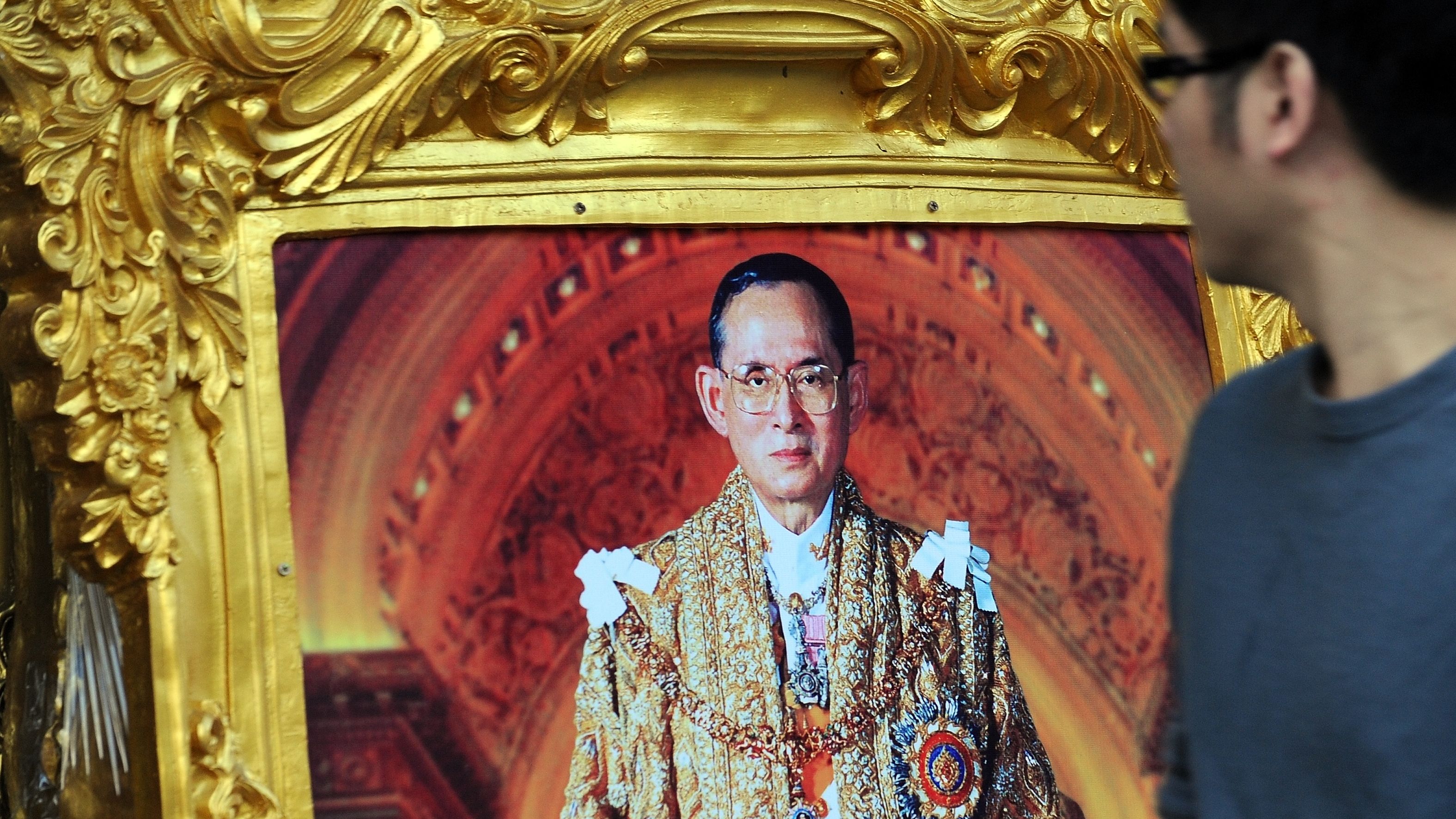 A Thai man walks past a photograph of King Bhumibol Adulyadej in Bangkok on the eve of his birthday on December 4, 2013. 