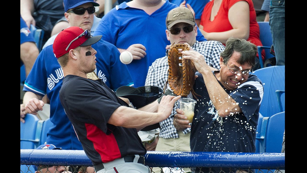 Minnesota Twins first baseman Justin Morneau, left, spills a fan's beer while chasing a foul ball during the first inning of an exhibition spring training game against the Toronto Blue Jays in Dunedin, Florida, on February 26.