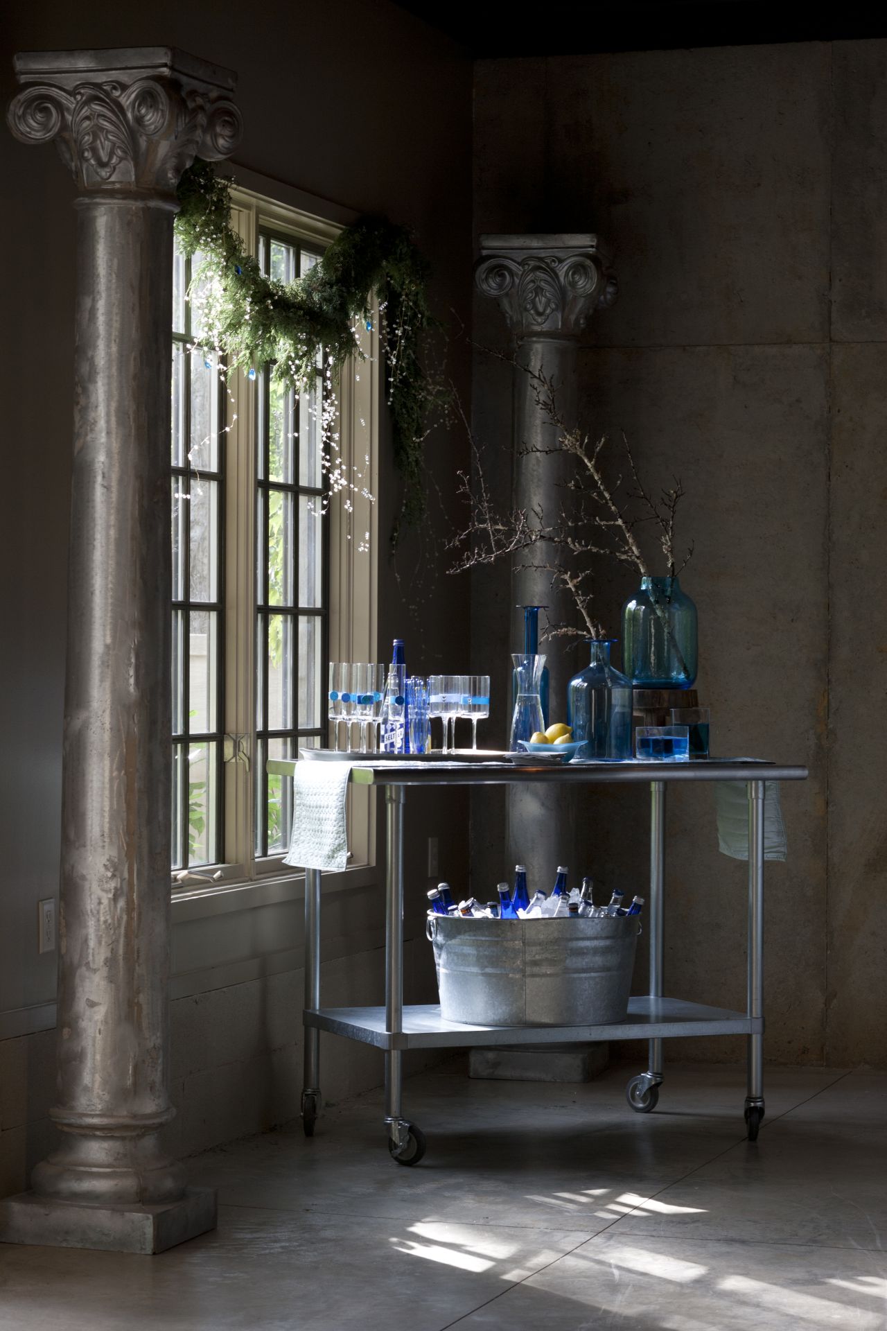 A sleek metal bar cart with blue glassware fits a modern or traditionally decorated space.