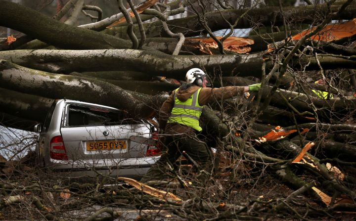 A man works to remove a tree that was blown over by the wind December 5, in Edinburgh, Scotland.