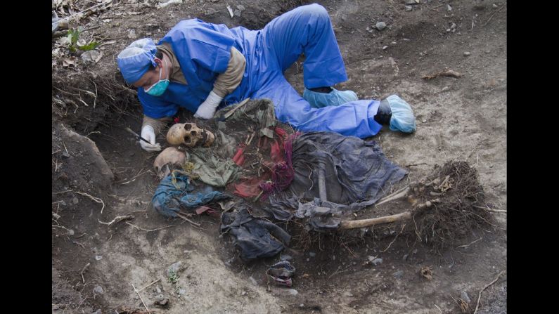 <strong>November 13:</strong> A member of a governmental forensic team unearths the remains of a mother and her teenage daughter from a shallow unmarked grave deep in the Amazonian jungle in southeastern Peru.